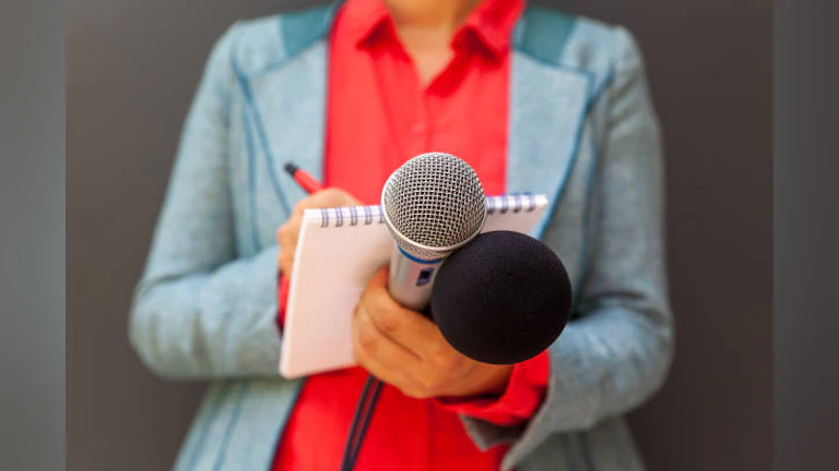Person holds microphones and notepad
