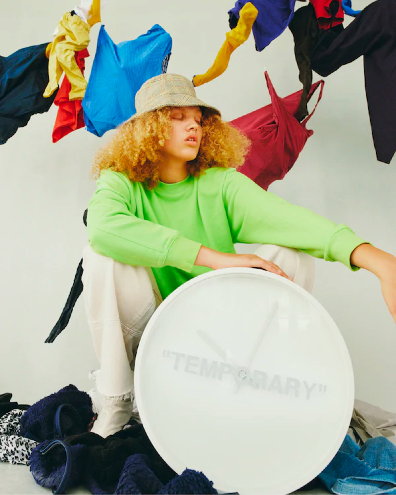 A woman sitting on the floor with a giant clock.